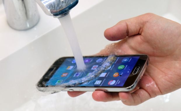 Samsung Galaxy S5 under a stream of water from a faucet